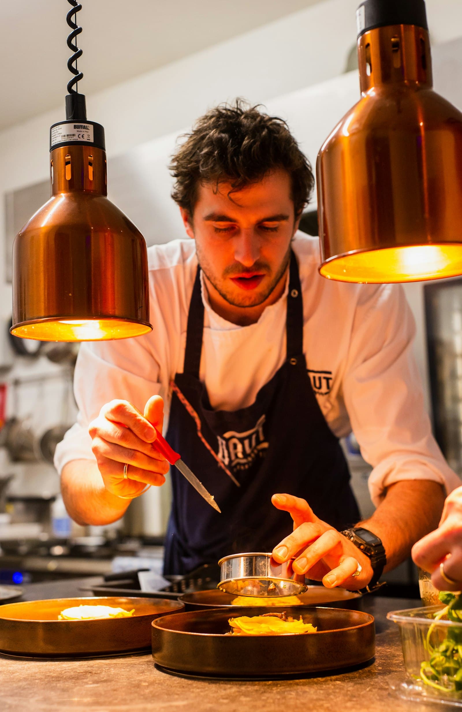 Stock photograph of a chef working at a pass; not Ember Table staff.